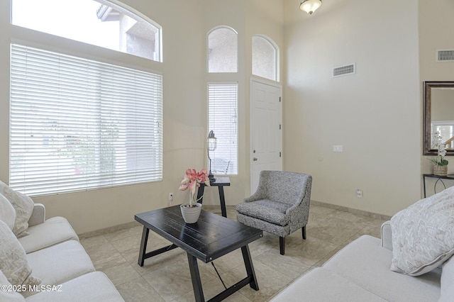 living room with a high ceiling, light tile patterned flooring, and plenty of natural light