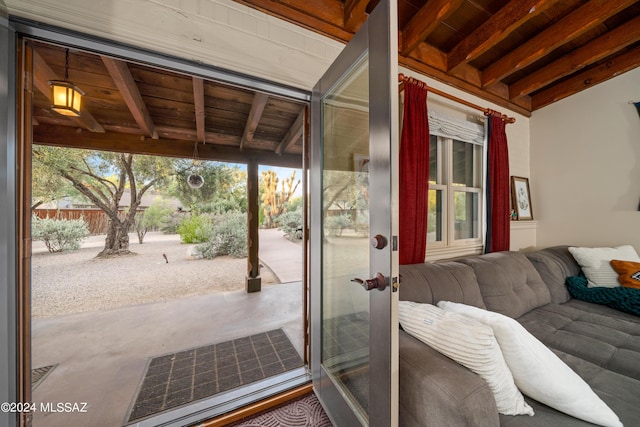 doorway to outside with concrete flooring, a wealth of natural light, and beam ceiling