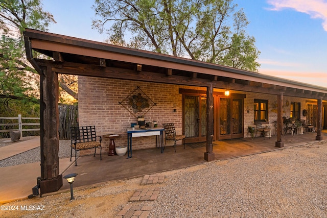 back house at dusk featuring a patio