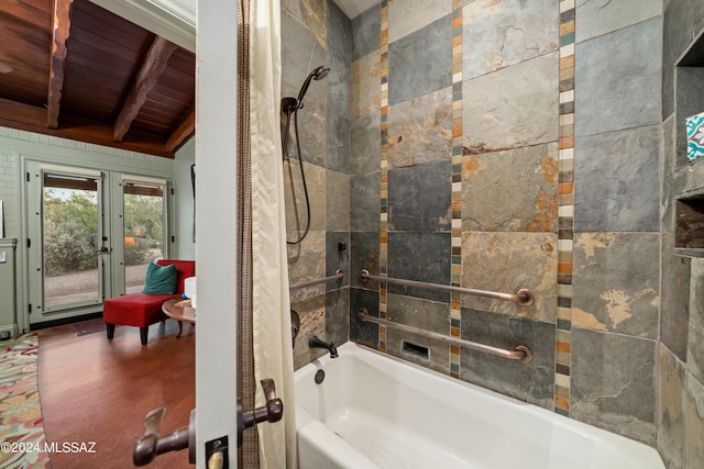 bathroom featuring french doors, wooden ceiling, tiled shower / bath combo, and beamed ceiling