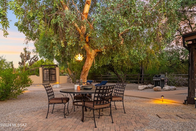 patio terrace at dusk featuring a grill