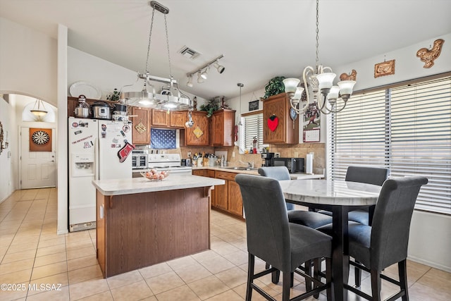 kitchen with white appliances, light tile patterned floors, hanging light fixtures, and backsplash