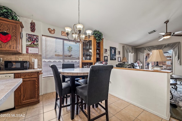 tiled dining area featuring lofted ceiling and ceiling fan with notable chandelier