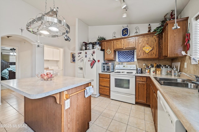 kitchen featuring pendant lighting, sink, white appliances, light tile patterned floors, and washer and dryer