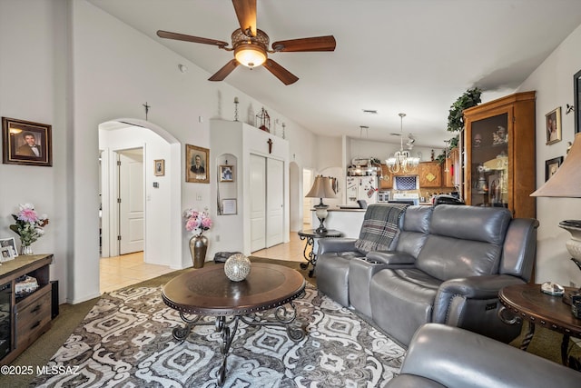 living room with lofted ceiling, light tile patterned floors, and ceiling fan with notable chandelier