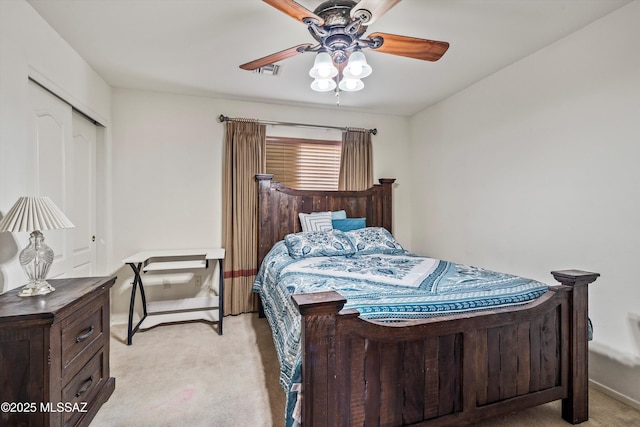 bedroom with ceiling fan, light colored carpet, and a closet