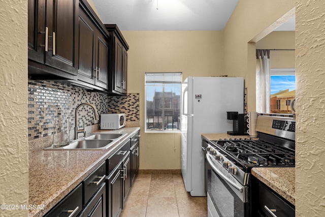 kitchen with stainless steel gas range oven, a healthy amount of sunlight, sink, and light stone counters