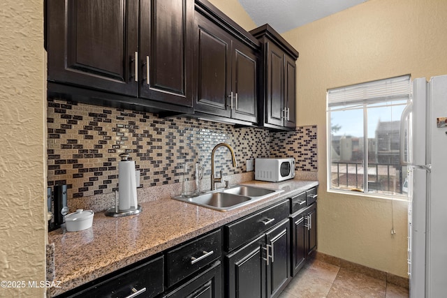 kitchen featuring light tile patterned flooring, sink, light stone counters, white appliances, and backsplash