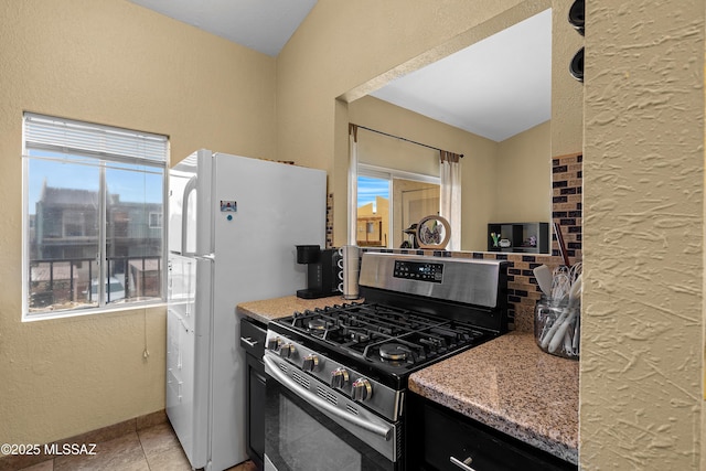 kitchen with white refrigerator, light tile patterned flooring, and gas stove