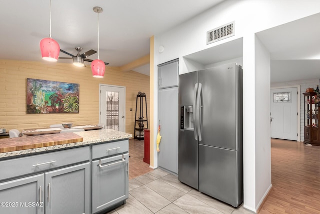 kitchen featuring pendant lighting, gray cabinetry, vaulted ceiling with beams, light stone countertops, and stainless steel fridge with ice dispenser