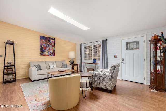 living room with lofted ceiling with skylight, brick wall, and wood-type flooring