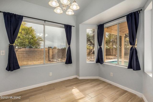 empty room featuring an inviting chandelier, lofted ceiling, and hardwood / wood-style floors