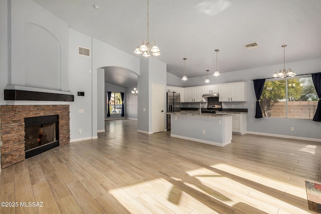 kitchen featuring stainless steel refrigerator with ice dispenser, a center island with sink, white cabinets, and a chandelier