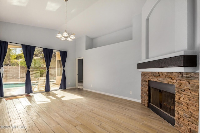 unfurnished living room featuring high vaulted ceiling, an inviting chandelier, a fireplace, and light hardwood / wood-style floors