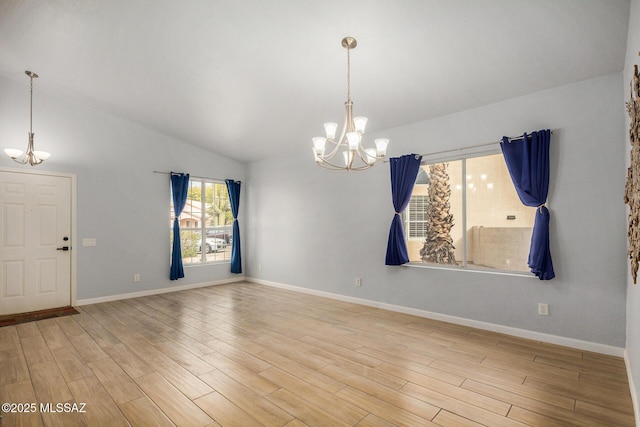 empty room with lofted ceiling, a notable chandelier, and light hardwood / wood-style flooring