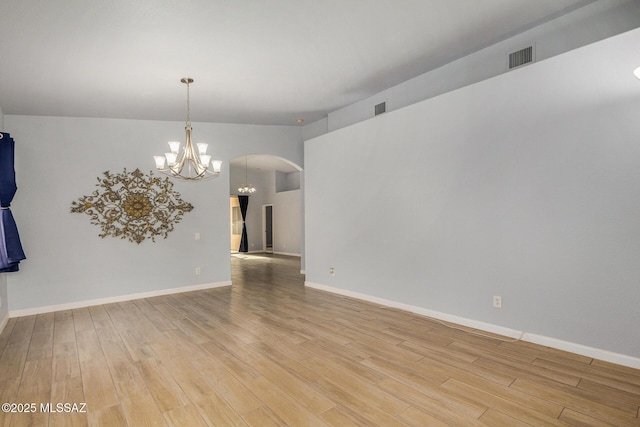 unfurnished room featuring a chandelier and light hardwood / wood-style flooring