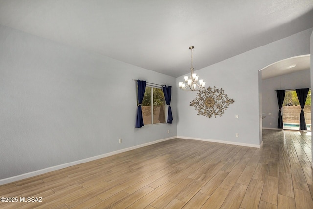 unfurnished room featuring lofted ceiling, a notable chandelier, and light hardwood / wood-style floors