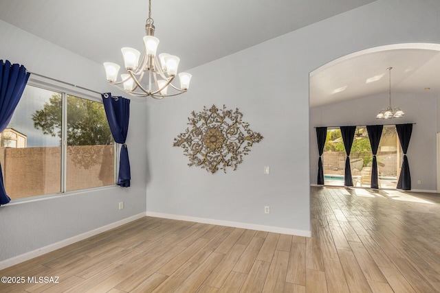 empty room featuring lofted ceiling, a chandelier, and light hardwood / wood-style floors