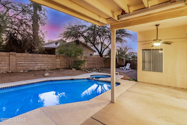 pool at dusk featuring ceiling fan and a patio