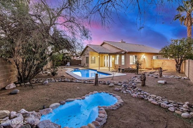 pool at dusk featuring a patio