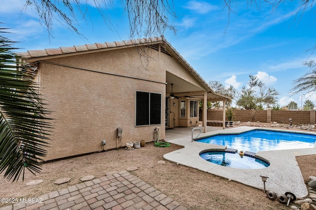 back of property with ceiling fan, a swimming pool with hot tub, and a patio