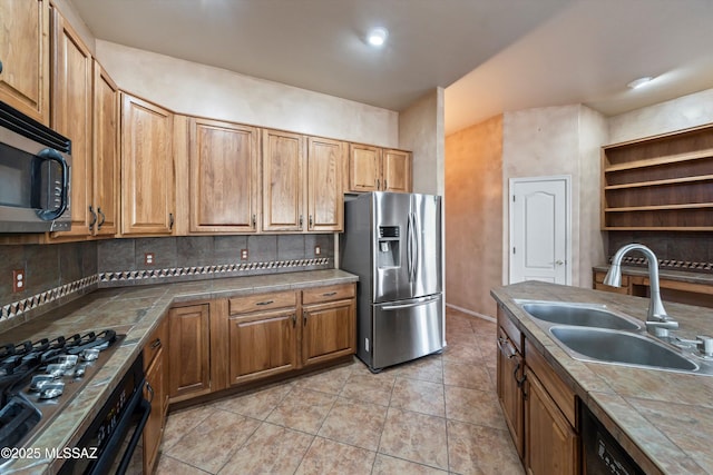 kitchen featuring appliances with stainless steel finishes, tile counters, sink, and decorative backsplash