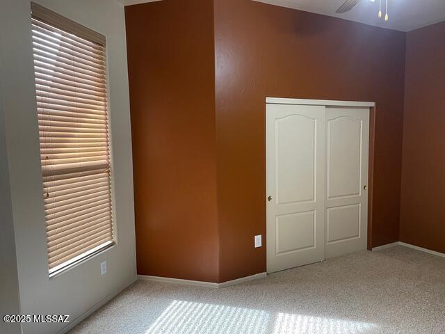 unfurnished bedroom with light colored carpet and a closet