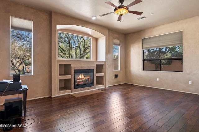 unfurnished living room with ceiling fan, dark hardwood / wood-style floors, a wealth of natural light, and a fireplace