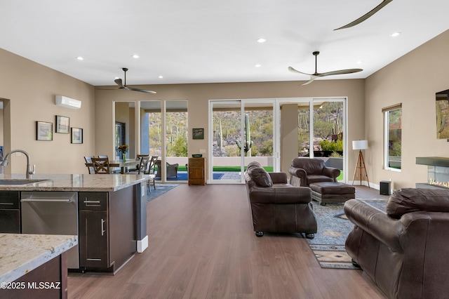 living room featuring hardwood / wood-style flooring, ceiling fan, sink, and a wealth of natural light