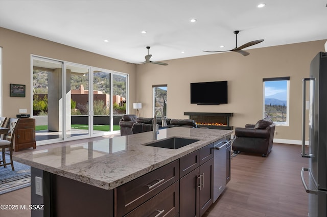 kitchen with dark brown cabinets, stainless steel appliances, sink, and a center island with sink