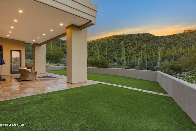 yard at dusk featuring a patio