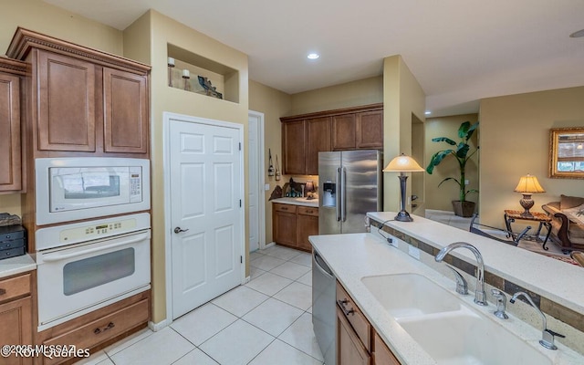 kitchen with light stone counters, appliances with stainless steel finishes, sink, and light tile patterned floors