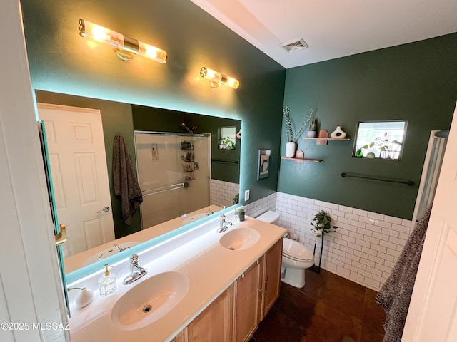 bathroom with a shower with shower door, tile walls, vanity, toilet, and tile patterned floors