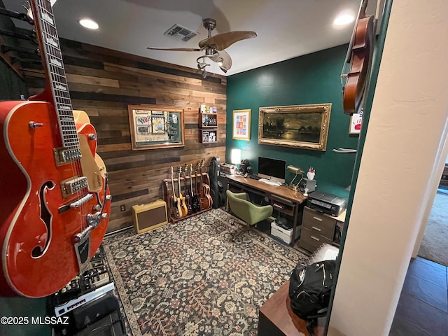 office area with ceiling fan and wood walls