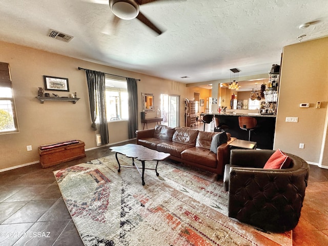 living room featuring ceiling fan, tile patterned flooring, and a textured ceiling