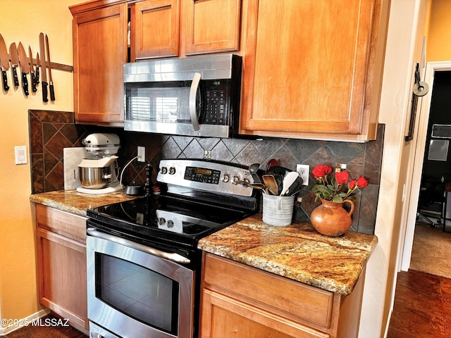 kitchen featuring stainless steel appliances, light stone countertops, and backsplash