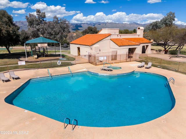 view of swimming pool with a playground and a mountain view