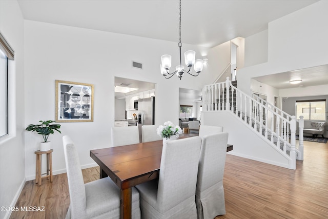 dining area with lofted ceiling, a chandelier, light hardwood / wood-style floors, and a wealth of natural light