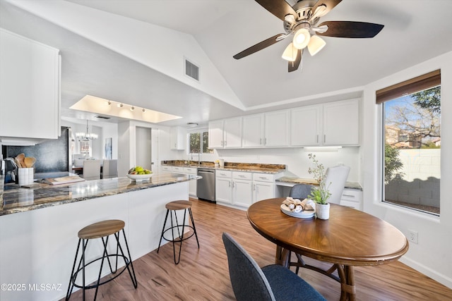 kitchen with a wealth of natural light, light stone countertops, stainless steel dishwasher, and white cabinets