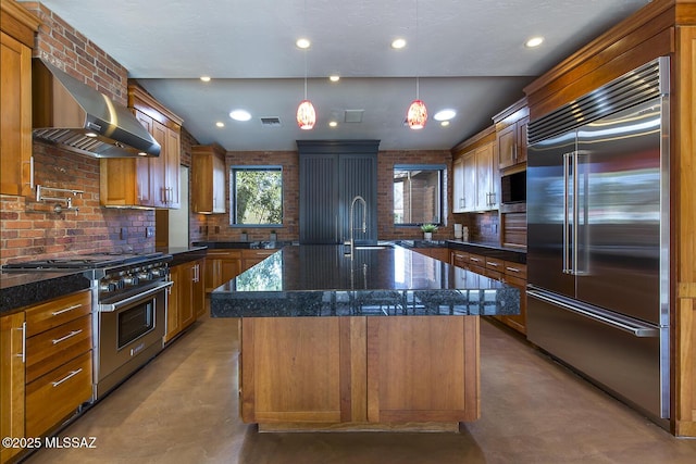 kitchen featuring high end appliances, finished concrete floors, an island with sink, dark stone counters, and wall chimney exhaust hood