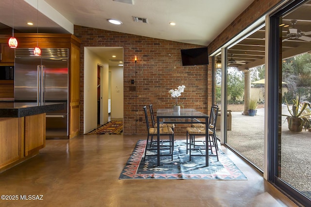 dining room featuring vaulted ceiling, brick wall, visible vents, and finished concrete floors