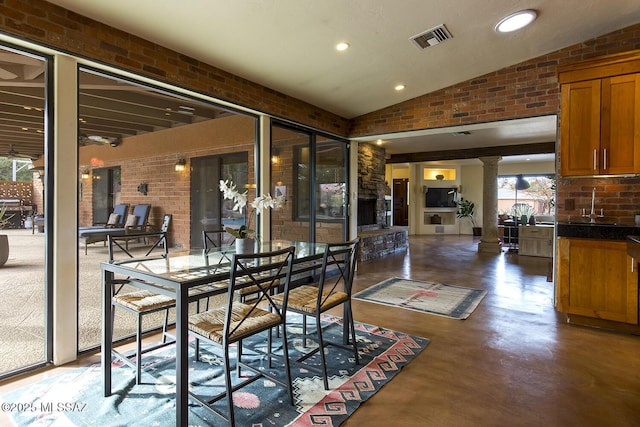 dining area featuring lofted ceiling, brick wall, visible vents, and ornate columns