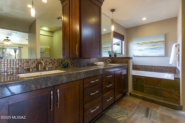 bathroom with a relaxing tiled tub, a sink, visible vents, backsplash, and double vanity