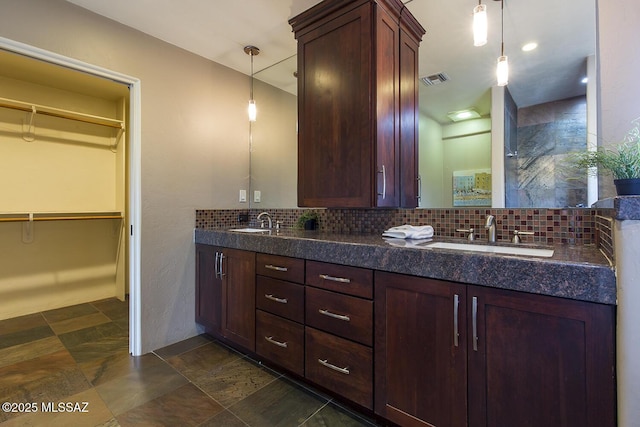 bathroom featuring backsplash, a sink, and a spacious closet