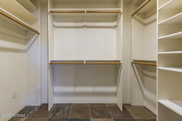 walk in closet featuring stone finish flooring