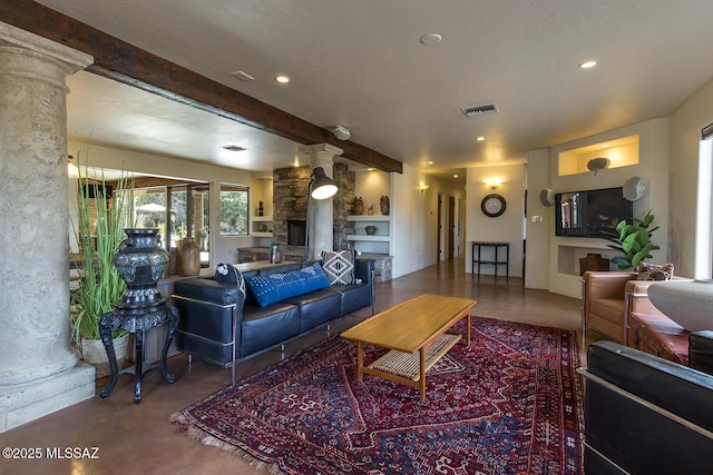 living area featuring visible vents, beamed ceiling, concrete flooring, a stone fireplace, and ornate columns