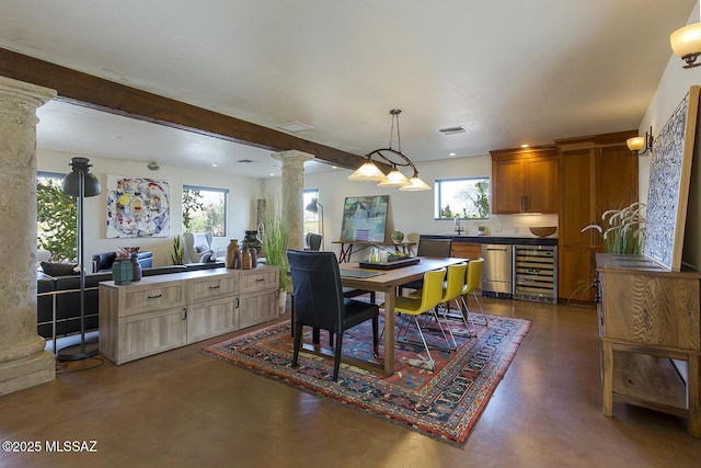 dining area with concrete flooring, wine cooler, visible vents, and ornate columns