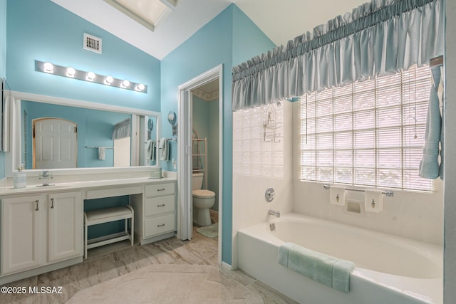 bathroom with vanity, a tub to relax in, and toilet