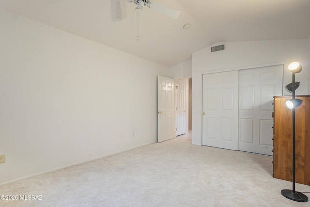 unfurnished bedroom featuring lofted ceiling, light carpet, ceiling fan, and a closet