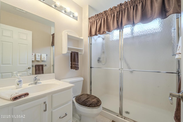 bathroom with toilet, vanity, and a shower with shower door